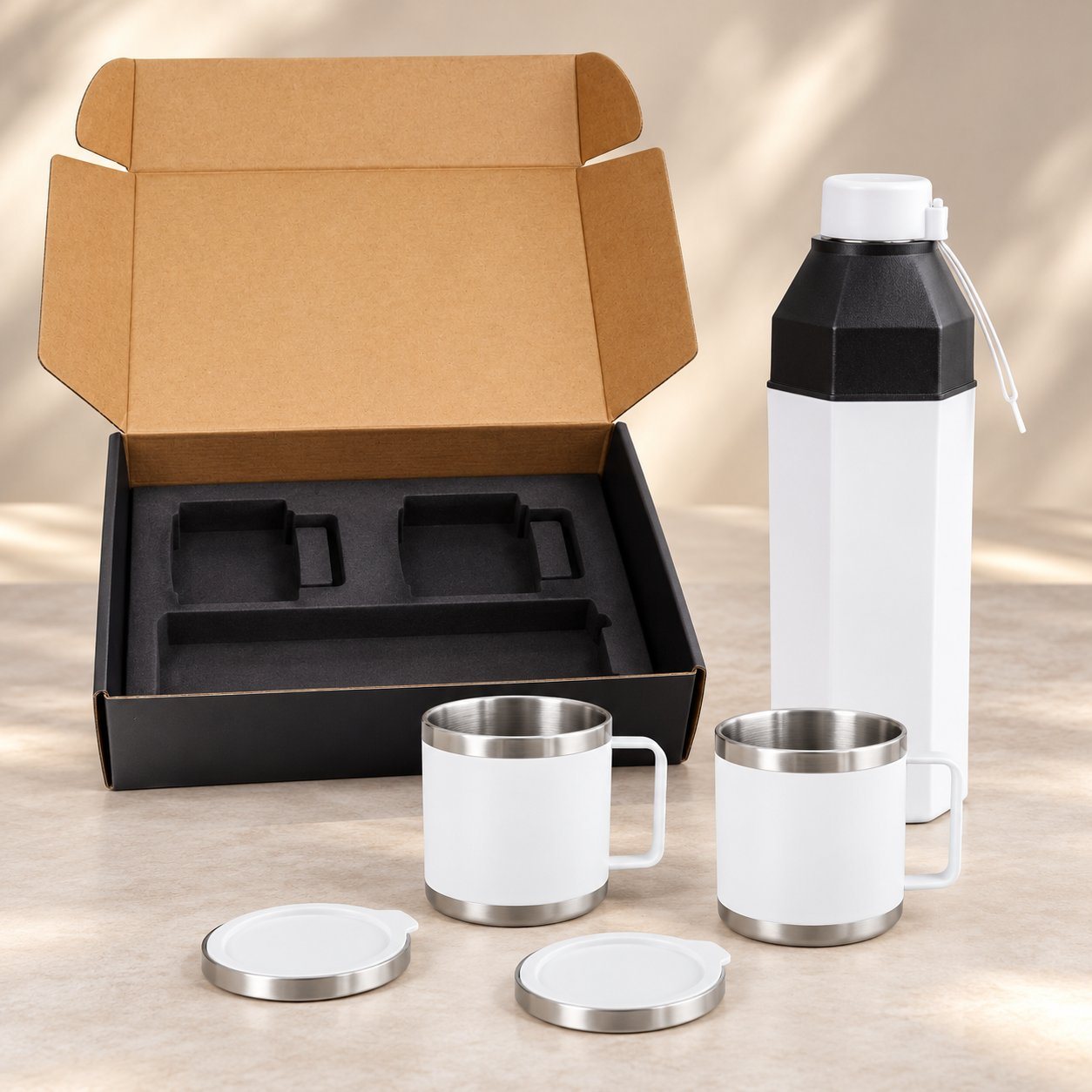 White insulated bottle with black hexagonal shoulder and two white steel cups with lids before an open gift box