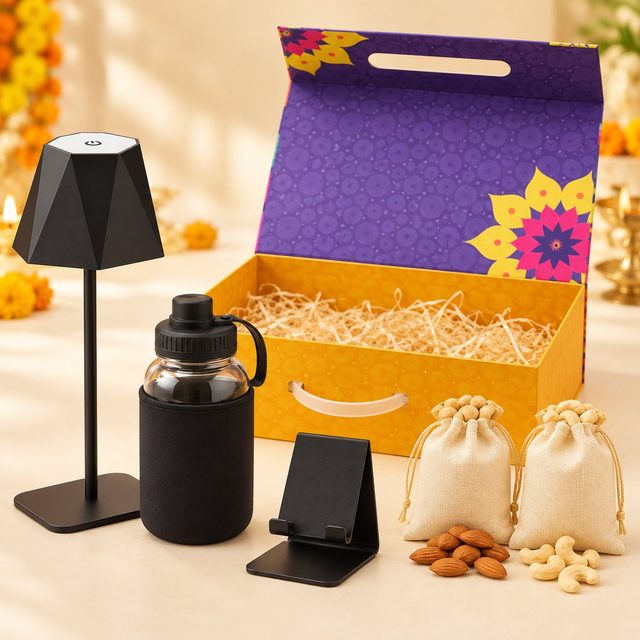 Celebrations set of 5: black table lamp, glass bottle in black sleeve, black mobile stand and almond and cashew pouches before a purple magnetic box