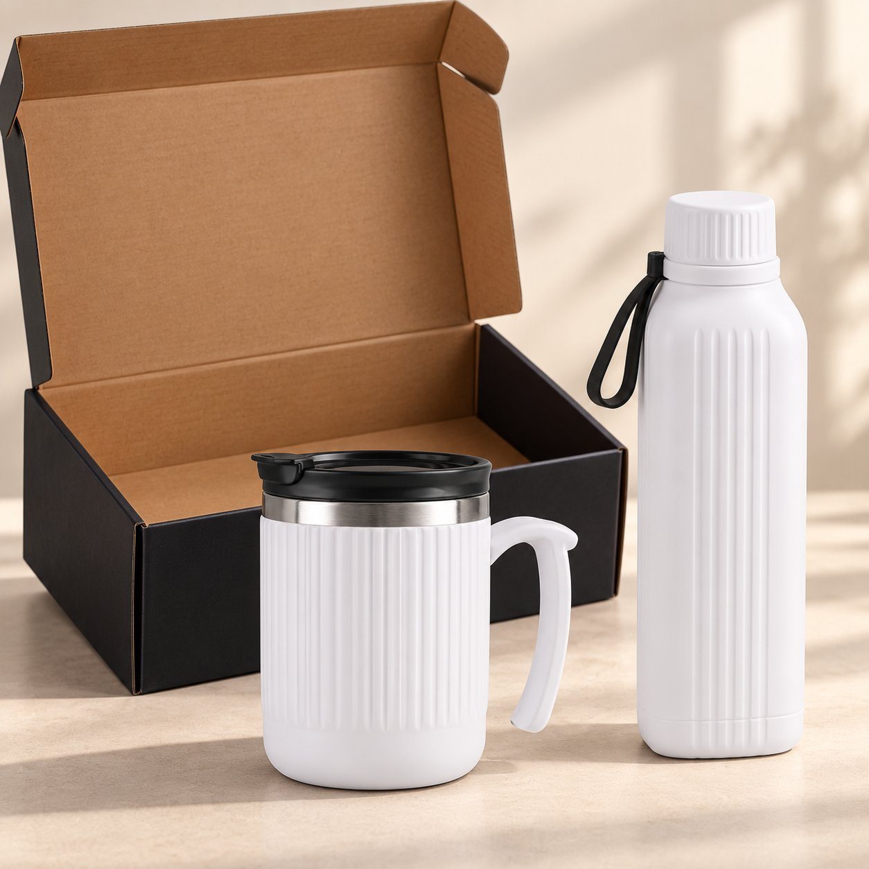 White square insulated bottle and white ribbed steel mug with lid in front of an open gift box